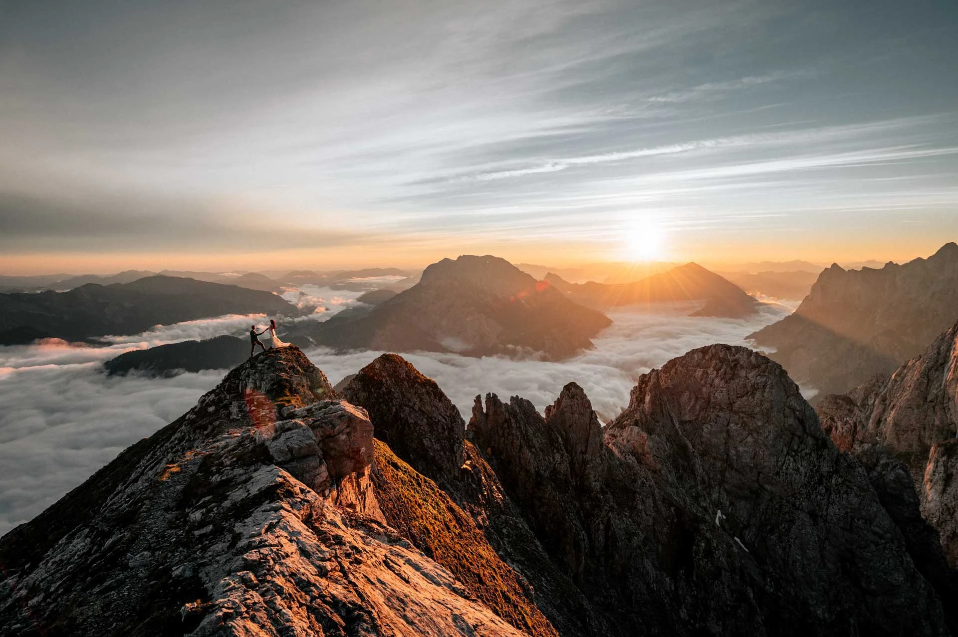 Couple on a ridge above fog at sunrise